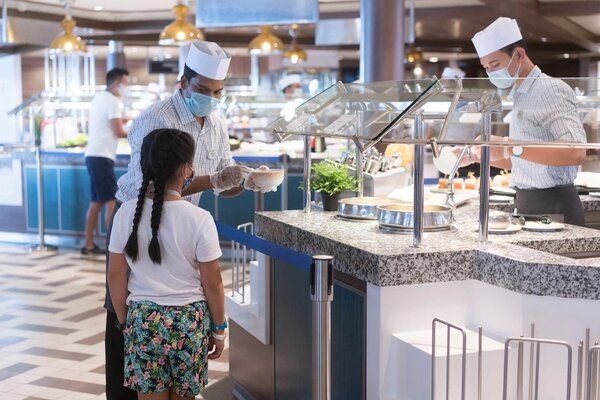 Mask wearing is compulsory like here, Crew member wear face masks at the Buffet area child getting served on a RCCL Ship