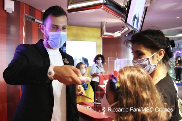 Crew member and passenger wearing a face masks, MSC Staff checking temperature onboard MSC Grandiosa, MSC Cruises | Riccardo Fani MSC Cruises 