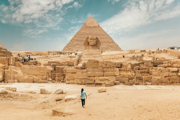 Cruise passenger on an excursion to Egypt walking to the Great Sphinx of Giza with the Giza Necropolis in the background. | By Spencer Davis Pexels 600x400