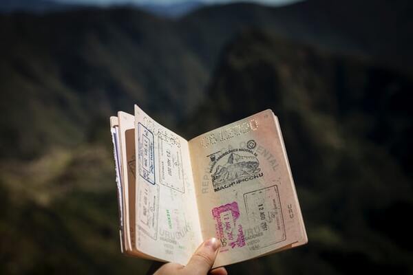 Lady Hand holding a passport with many stamps | by Agus Dietrich UP 600x400