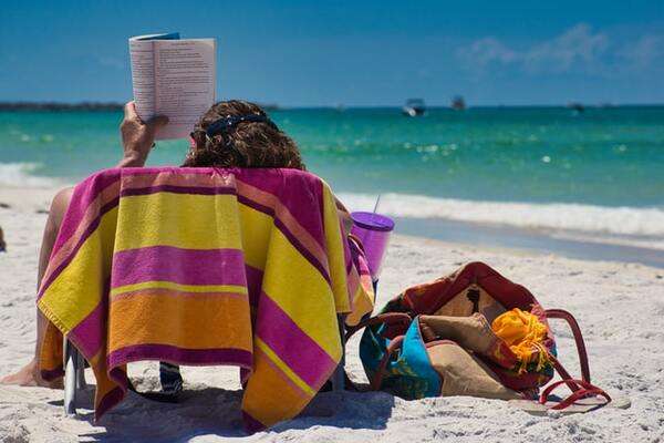 Lady lying down reading a book on a beach in Bahamas, Caribbean | by Craig Cameron 600x400