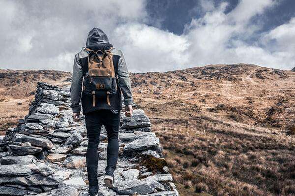 Young man walking up the hill with carry-on back-pack | by Andreas Wagner 600x400
