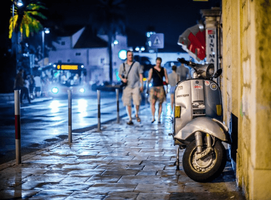 Rome by night showing a scooter with 2 man walking down the street