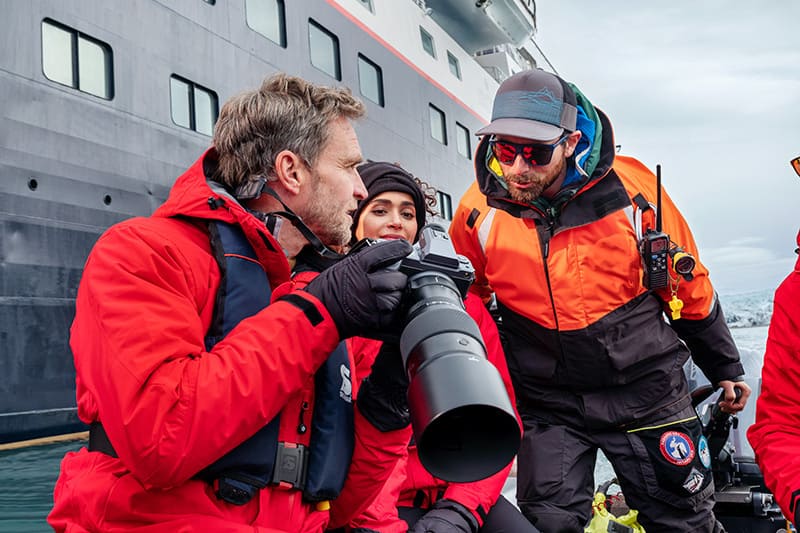 A group of guests are seen on board a Zodiac in Bellsund, Svalbard, preparing for a shore excursion. The Silver Cloud ship is behind.