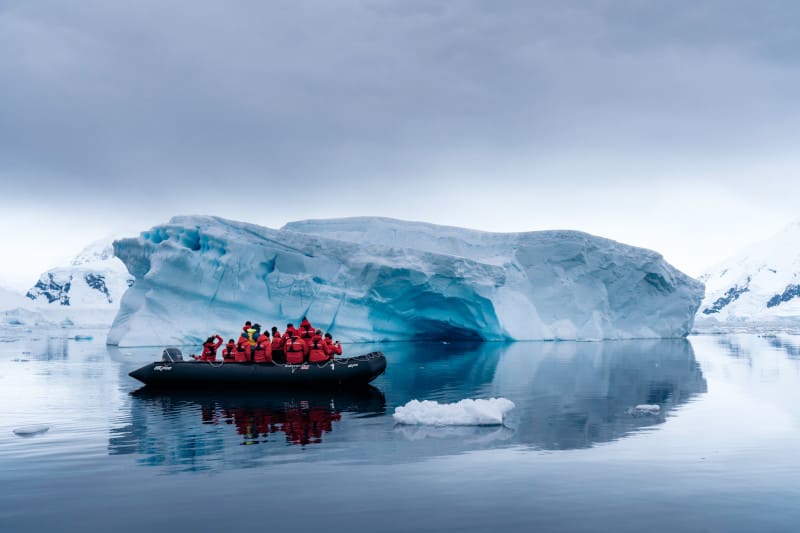 Guests aboard a zodia in Antarctica enjoy a calm morning past an icebergs. On an shore excursions with a Silversea expedition ship