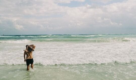 father caring a child into the ocean on Pomene