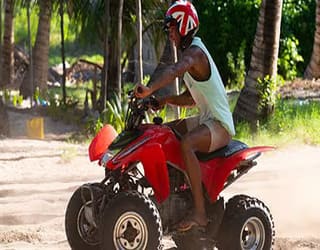 Red quad bike driven by a man with Uk helmet. On an MSC orchestra cruise to the unexplored coral reefs and most picturesque sites of Pomene