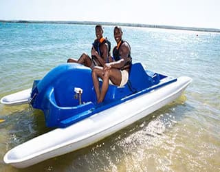 2 man on a Pedalo boat to illustrate the pedalo rental experience on a cruises from Durban South Africa - you can see the MSC orchestra in the background in very small